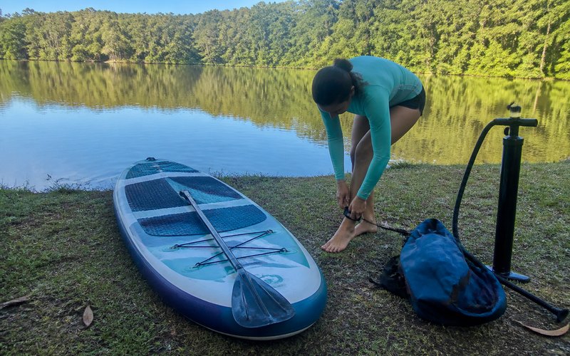 SUP-Board mit Paddel am Ufer eines Sees